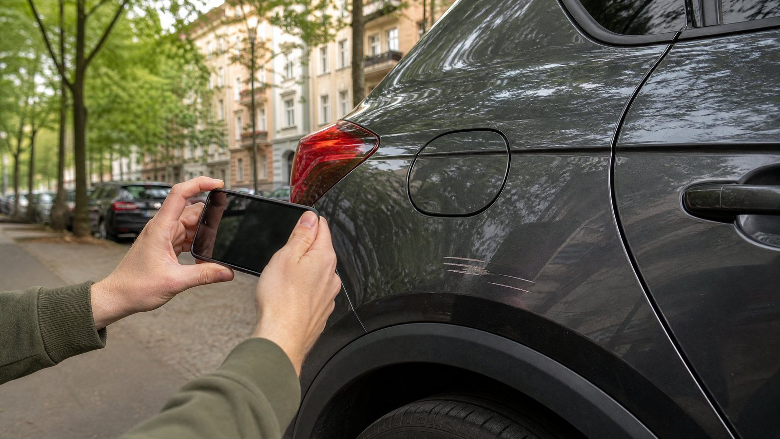 Fahrzeughalter fotografiert einen kleinen Parkschaden am Auto